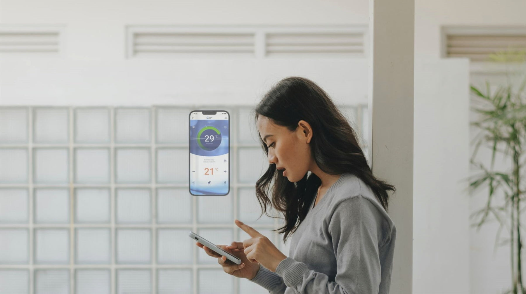 A woman is adjusting the temperature of her heat pump system using a thermostat app on her smartphone.